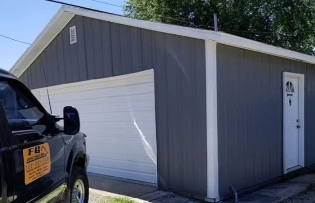 Gray detached garage with a white overhead door and side entry door